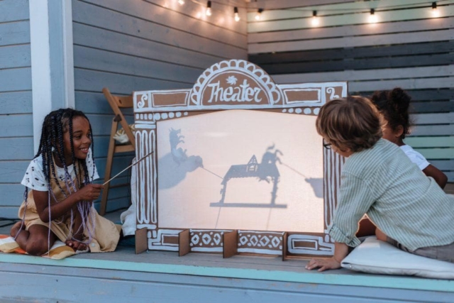 Two children playing with a Puppet Theater made from moving boxes.