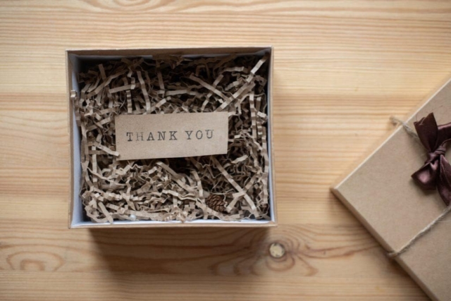 A cardboard box with a cardboard thank you note inside.