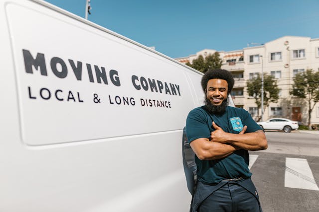 Professional mover standing next to a van with his arms crossed